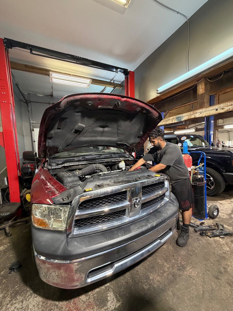 ABF technician working under the hood of a red Ram truck inside the shop